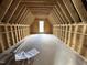Unfinished attic space showcasing wooden beams, studs, and a window providing natural light at 4905 Hidden Pasture Way, Zebulon, NC 27597