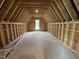 Spacious unfinished attic shows the frame of the home with exposed wooden beams and a window at the far end at 4905 Hidden Pasture Way, Zebulon, NC 27597