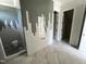 Sleek bathroom boasting an open shower with unique tiling, complemented by marble flooring and a peek into walk-in closet at 4905 Hidden Pasture Way, Zebulon, NC 27597