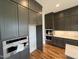 Modern kitchen boasts gray cabinets, stainless steel appliances, and hardwood floors at 4905 Hidden Pasture Way, Zebulon, NC 27597