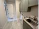 A cozy laundry room boasts a wash sink, modern gray cabinets and stylish marbled floors at 4905 Hidden Pasture Way, Zebulon, NC 27597