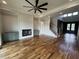 Open living room with fireplace, custom cabinets, ceiling fan, and staircase access to upper floors at 4905 Hidden Pasture Way, Zebulon, NC 27597