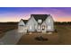Beautifully landscaped modern farmhouse with a three-car garage, set against a picturesque sunset backdrop at 4909 Hidden Pasture Way, Zebulon, NC 27597