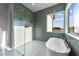 Walk in shower features teal accent tiling and a glass partition, with a tub in the background at 4909 Hidden Pasture Way, Zebulon, NC 27597