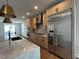 Modern kitchen featuring stainless steel appliances, wood cabinets, and a spacious center island with marble countertops at 11548 Helmond Way # 120, Raleigh, NC 27617