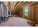 Unfinished attic space with exposed rafters, insulation, and a window at 65 Diamond Creek Dr, Zebulon, NC 27597