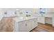 Open kitchen with island, white cabinets, wood floors, and modern appliances at 305 Chestnut Oak Ln, Lillington, NC 27546