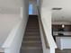 Carpeted staircase with white walls and wooden handrail leading to the upper level at 32 Furley St., Homesite 53, Sanford, NC 27330