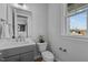 Well-lit half bathroom with a modern vanity, decorative mirror, and a window providing natural light at 110 Summerlin Dr, Clayton, NC 27527