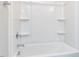 Close-up of a clean, white bathtub and shower with shelving and chrome fixtures in a well-lit bathroom space at 1156 Cottonsprings Dr, Wendell, NC 27591
