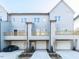 Three-story townhome featuring a two-car garage, a small wooden balcony, and gray siding at 1156 Cottonsprings Dr, Wendell, NC 27591