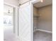 Bright mudroom featuring gray tiled floors, a storage closet, and decorative sliding barn door to the living area at 1156 Cottonsprings Dr, Wendell, NC 27591