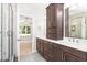 Bathroom featuring wood cabinets, double sinks, a walk-in shower, and an open doorway to the bedroom at 3402 St Barts Pl, Mebane, NC 27302