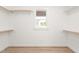 Bright walk-in closet featuring custom shelving, a window, and hardwood floors at 3402 St Barts Pl, Mebane, NC 27302