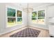 Bright dining area with natural light, modern chandelier, and backyard views through large windows at 3402 St Barts Pl, Mebane, NC 27302