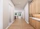 Long hallway with wood floors, wooden storage cabinet with marble top, and view to the kitchen and living room at 154 Colonial Trail Ct, Pittsboro, NC 27312