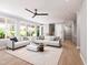 Bright living room featuring neutral furniture, large windows, and hardwood floors under a ceiling fan at 154 Colonial Trail Ct, Pittsboro, NC 27312