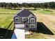 Aerial view of gray home featuring a two-car garage and pristine landscaping with golf course backdrop at 592 Barbour Farm Ln, Four Oaks, NC 27524