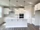 Modern white kitchen featuring stainless steel appliances, center island with pendant lights, and hardwood flooring at 592 Barbour Farm Ln, Four Oaks, NC 27524