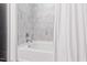 White bathtub with shower head and grey tiled wall, partially obscured by white shower curtain at 1300 St Marys St # 208, Raleigh, NC 27605