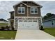 Two-story home with stone accents and a large white two car garage door and concrete driveway at 316 Bishop Ln, Sanford, NC 27330