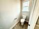 Functional toilet featuring neutral walls, tile flooring, and a bright window at 316 Bishop Ln, Sanford, NC 27330