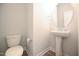 Modern powder room with pedestal sink, round mirror, and wood-look flooring at 196 Abingdon Farms Dr, Selma, NC 27576