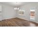 Bright dining area featuring laminate wood floors, a modern chandelier, and a window overlooking backyard at 232 Berry Mill Ln # 201, Raleigh, NC 27603