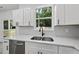 Modern kitchen features white cabinetry, stainless steel appliances, and a large window overlooking a wooded backyard at 242 Sequoia Dr, Louisburg, NC 27549