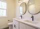 Elegant bathroom featuring dual sinks with black fixtures, oval mirrors, and sleek white cabinetry at 30 Tamaran Ct, Spring Hope, NC 27882