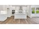 Modern kitchen features all-white cabinetry, stainless steel appliances, and a center island with a sink at 736 Heathered Farm Way, Apex, NC 27523