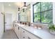 Modern bathroom featuring a long vanity with double sinks, decorative lighting, and a large window with a view at 1000 Marilyn Dr, Raleigh, NC 27607