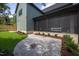 Stone patio leading to a screened-in porch, surrounded by lush landscaping and greenery at 1000 Marilyn Dr, Raleigh, NC 27607