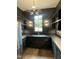 Dark scullery featuring black cabinets, open shelving, stainless steel refrigerator and modern lighting at 1000 Marilyn Dr, Raleigh, NC 27607