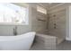 Modern bathroom with a large walk-in shower, standalone bathtub, and neutral-toned tiling at 155 Gaines Trl, Pittsboro, NC 27312