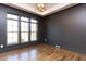 A room with a modern chandelier, three large windows, dark walls, and hardwood floors at 155 Gaines Trl, Pittsboro, NC 27312
