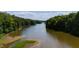 Expansive aerial view of a lake surrounded by dense green forests and partially exposed shoreline on a sunny day at 1820 Oatlands Court Ct, Wake Forest, NC 27587