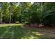 A lush backyard offers a peaceful retreat with mature trees, a well-manicured lawn, and Adirondack chairs at 1820 Oatlands Court Ct, Wake Forest, NC 27587