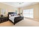 Well-lit bedroom featuring neutral carpet, a ceiling fan, large windows, and a dark wood bed frame at 1820 Oatlands Court Ct, Wake Forest, NC 27587