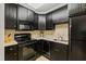 Compact kitchen with black appliances, dark cabinetry, neutral counter tops and ceramic tile back splash at 1820 Oatlands Court Ct, Wake Forest, NC 27587