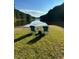 Scenic lake view with chairs on the grassy shore offering a peaceful retreat surrounded by nature and clear skies at 1820 Oatlands Court Ct, Wake Forest, NC 27587
