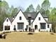 Stunning new construction home featuring a white brick facade, dark window trim, and lush landscaping at 7621 Falls Creek Ln, Raleigh, NC 27614