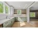 Modern kitchen featuring sage-green cabinets, white countertops, and lots of natural light at 7621 Falls Creek Ln, Raleigh, NC 27614