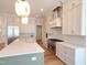 Kitchen with stainless appliances, white cabinetry, large island, stone countertops, and modern pendant lighting at 7621 Falls Creek Ln, Raleigh, NC 27614