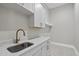 A well-lit laundry room offers white cabinets, a quartz countertop, and modern fixtures for efficient chores at 7621 Falls Creek Ln, Raleigh, NC 27614