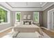 Luxurious main bedroom featuring a tray ceiling, hardwood floors, and expansive windows offering natural light at 7621 Falls Creek Ln, Raleigh, NC 27614