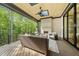 Covered porch with outdoor seating, fireplace, ceiling fan, and views of the surrounding woods at 7621 Falls Creek Ln, Raleigh, NC 27614