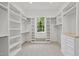Bright walk-in closet provides ample storage with custom shelving, drawers, and natural light from a window at 7621 Falls Creek Ln, Raleigh, NC 27614