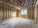 Unfinished bedroom with wood framing, plywood flooring, a window, and exposed ceiling beams at 2728 Trifle Ln, Wake Forest, NC 27587