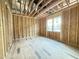 Unfinished bedroom showing exposed framing, wood subfloor, and rough openings for windows and electrical at 2728 Trifle Ln, Wake Forest, NC 27587